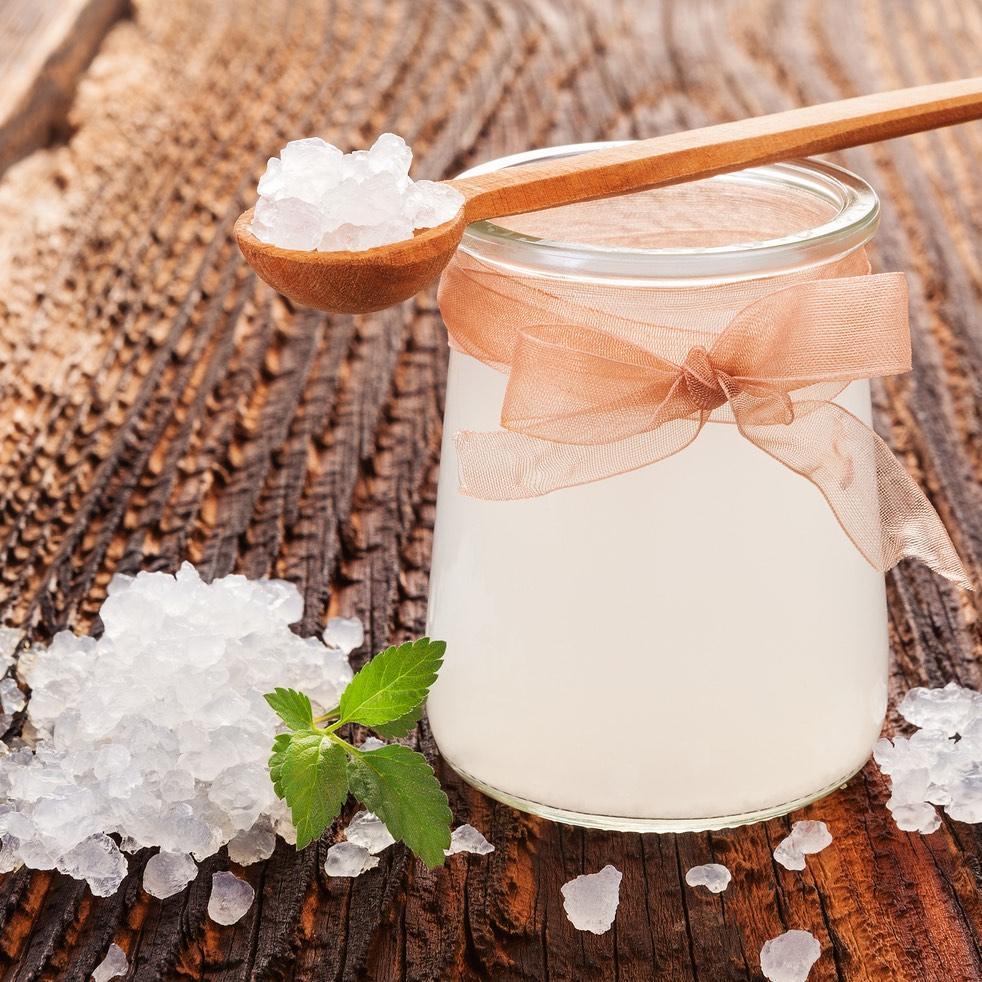 Water kefir grains with wooden spoon and background with glass jar of water kefir